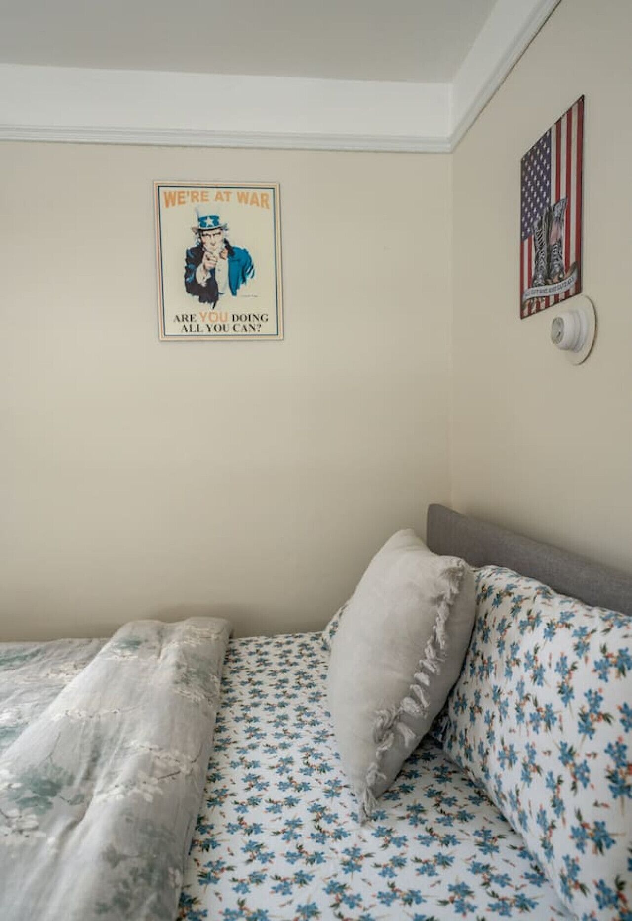 Une chambre à coucher avec un lit, un oreiller, une affiche et un drapeau américain.