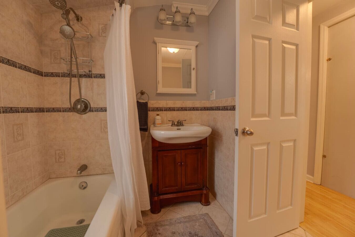 A bathroom with a bathtub, shower, sink, and a door.