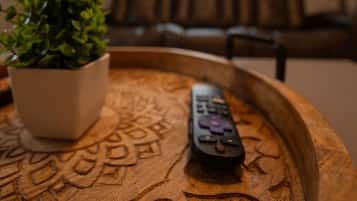 Une télécommande posée sur un plateau en bois, à côté d’une plante en pot.