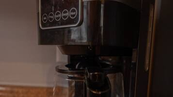 A stainless steel coffee maker with a digital control panel and a clear carafe.