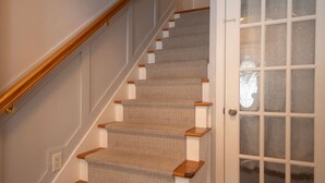 A staircase with carpeted steps and wooden handrails, leading to a door with glass panels.