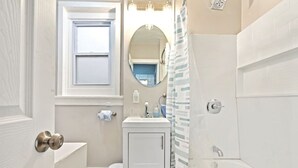 Un baño con inodoro, lavabo, espejo y ducha.