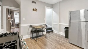 Una cocina con una mesa de comedor, sillas, un refrigerador y un letrero que dice 'EAT'.