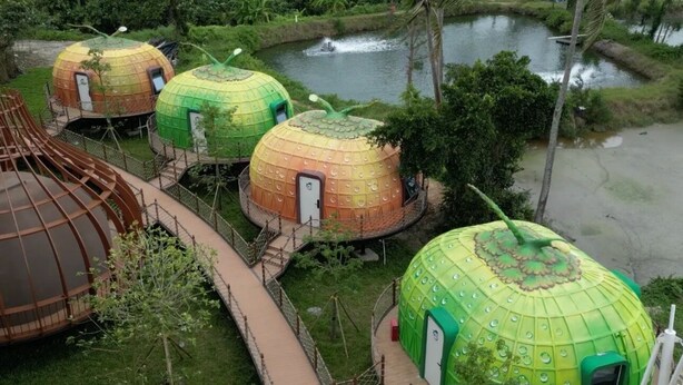 A series of dome-shaped yurts with a central walkway connecting them, surrounded by greenery and a body of water. - Unicorn Rocket Resort (Wenchang)