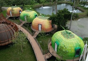 A series of dome-shaped yurts with a central walkway connecting them, surrounded by greenery and a body of water. - Unicorn Rocket Resort (Wenchang)