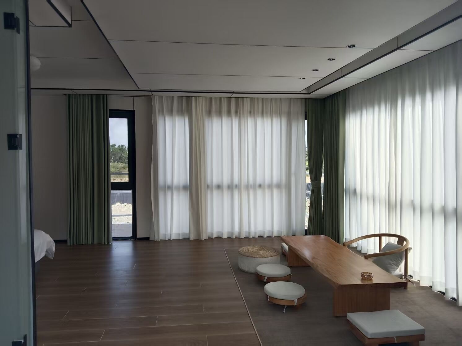 A modern living room with a wooden floor, a long wooden table, and a cushioned bench.