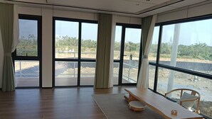 A spacious room with large windows, a wooden bench, and a chair. - Unicorn Rocket Resort (Wenchang)