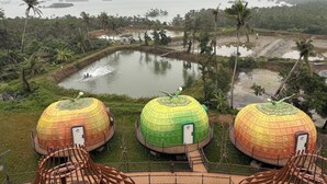 Three dome-shaped structures with doors, surrounded by a water body and greenery, with a distant view of a coastline. - Unicorn Rocket Resort (Wenchang)