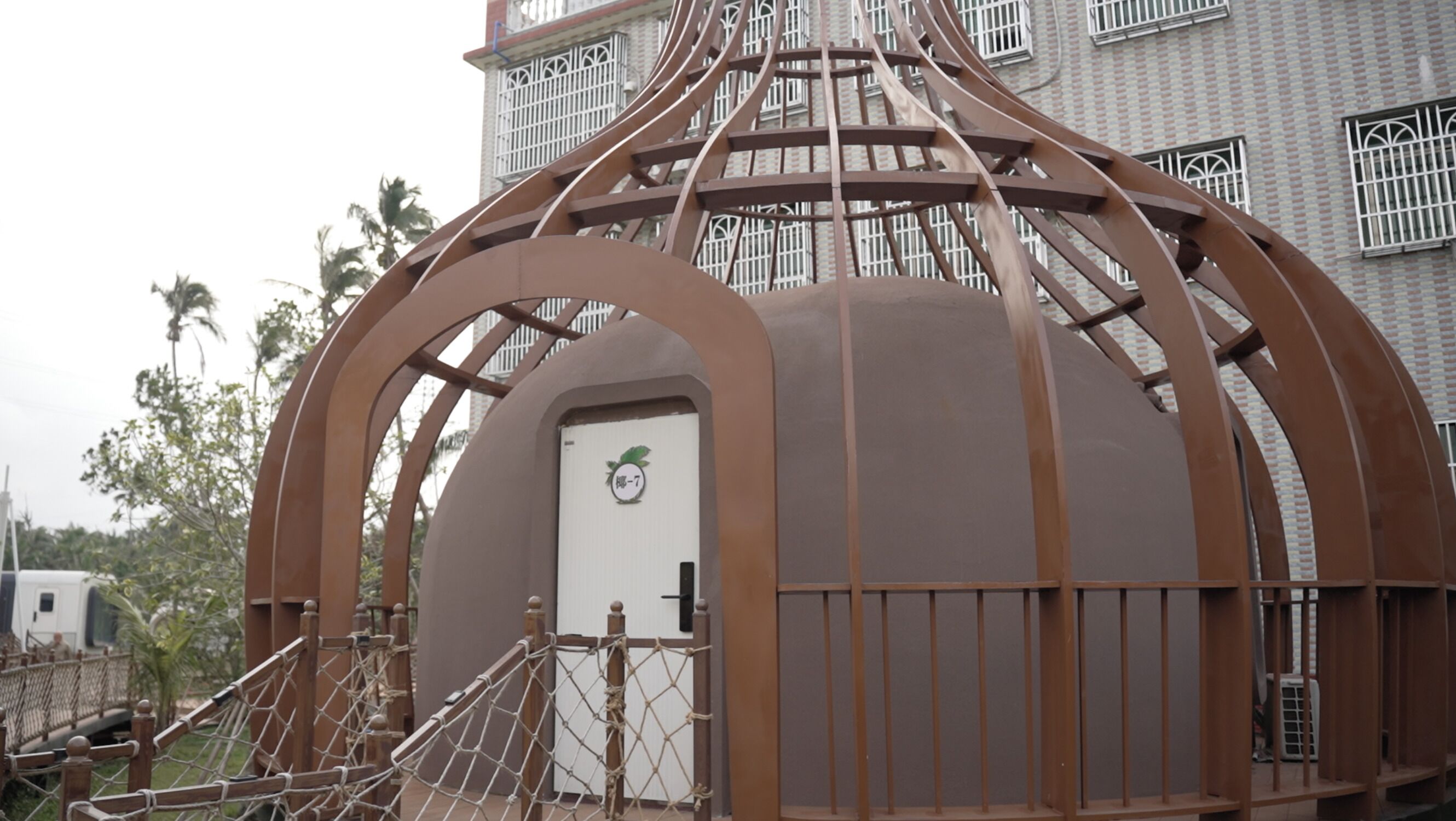 Una estructura en forma de cúpula con una puerta, rodeada por una cerca de metal y escaleras de madera.