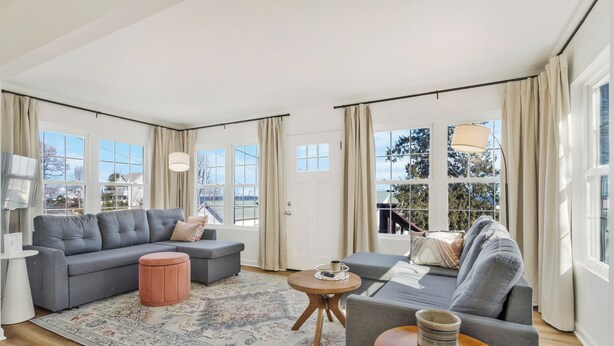 A spacious living room with a grey sectional sofa, a round wooden coffee table, and a patterned rug. - Kick back and enjoy the Chesapeake & this 3-bedroom, relaxing, stylish space. (Prince Frederick)