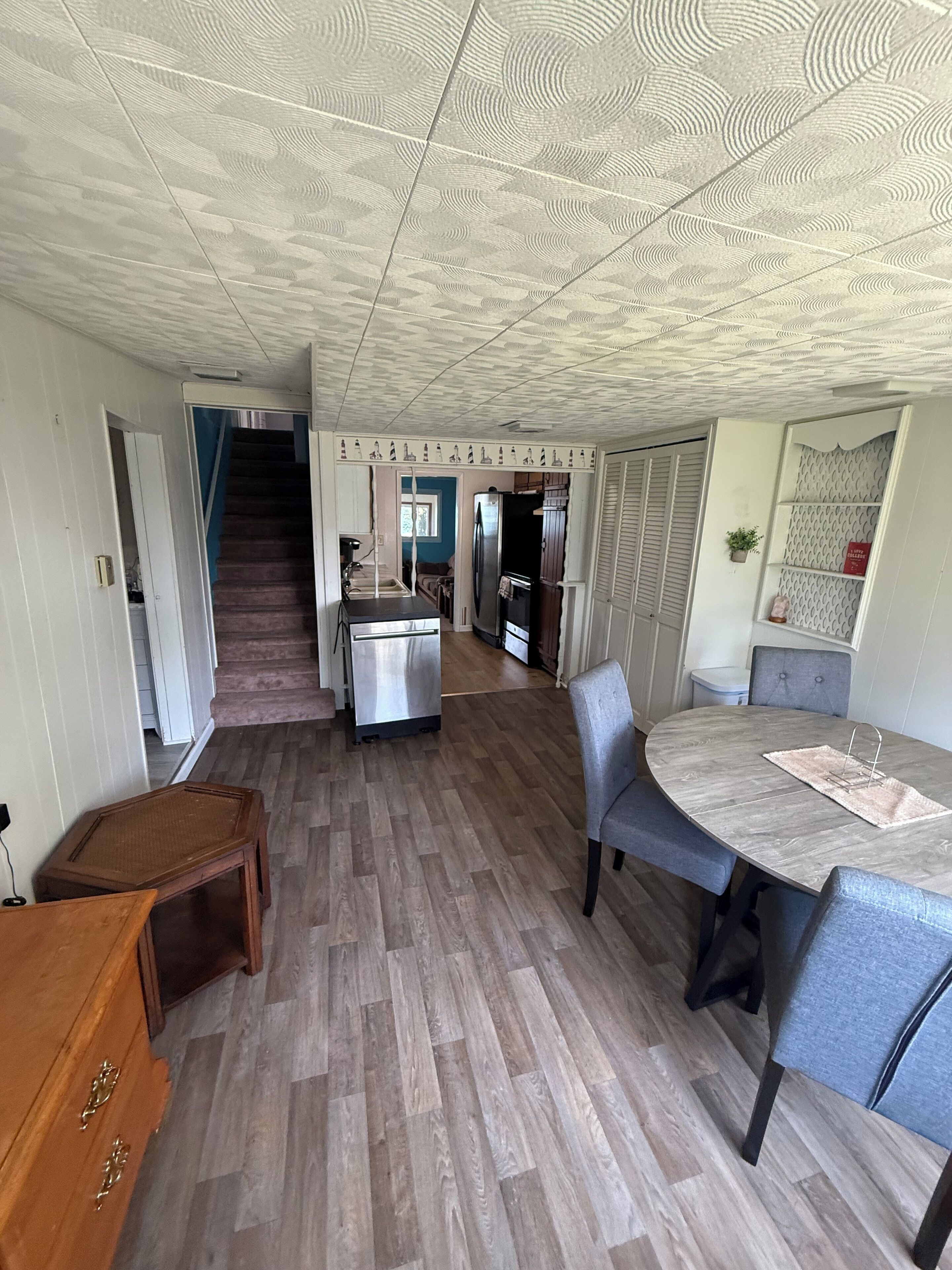 Une cuisine spacieuse dotée d’un îlot central, un coin repas avec une table ronde et un escalier menant à un autre niveau.