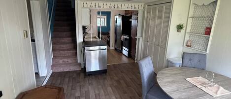 Une cuisine spacieuse dotée d’un îlot central, un coin repas avec une table ronde et un escalier menant à un autre niveau.
