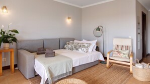 Een moderne slaapkamer met een slaapbank, een nachtkastje met een lamp en een stoel met een mand.