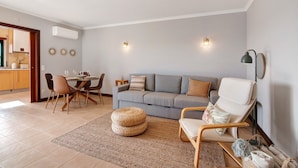Een woonkamer met een bank, stoelen, een eettafel en een keuken op de achtergrond.