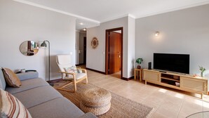 Een woonkamer met een bank, een stoel, een televisie en een houten kast.