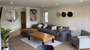 A modern living room with a grey sectional sofa, a wooden coffee table, and a large mirror.
