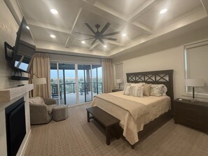 A spacious bedroom with a large bed, a flat-screen TV mounted on the wall, a fireplace, and a balcony with a view. - River front w/ view of Tetons - Fall River Vista (Ashton)