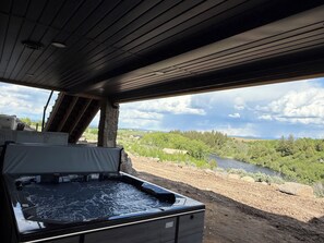 A hot tub in a rustic cabin with a scenic view of a river and forest. - River front w/ view of Tetons - Fall River Vista (Ashton)