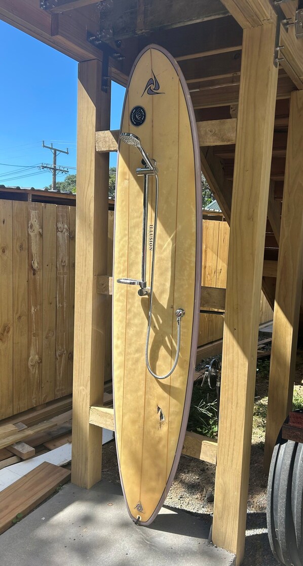 A wooden structure with a showerhead and hose, likely a shower stall or a similar facility.