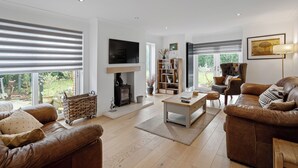 Una sala de estar moderna con chimenea, sofás de cuero, una mesa de centro y una estantería.