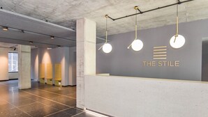 Et receptionsområde med moderne design, med en receptionsdisk, et vægmonteret logo og hængende lamper.