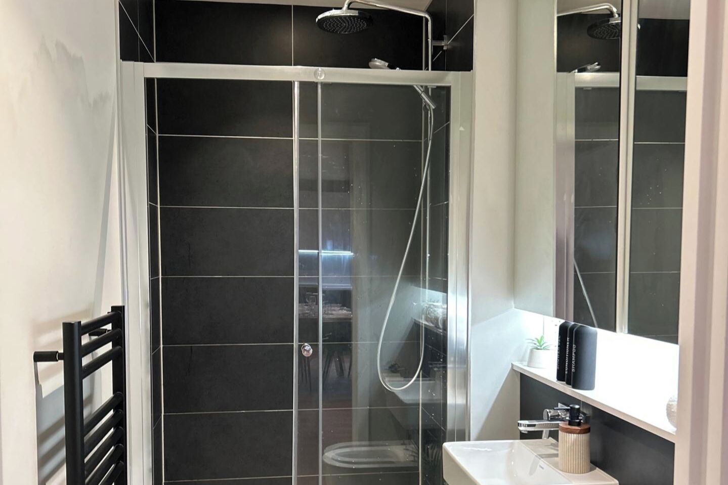 Ein modernes Badezimmer mit einer gläsernen Dusche, einem weißen Waschbecken und einem Spiegel darüber.