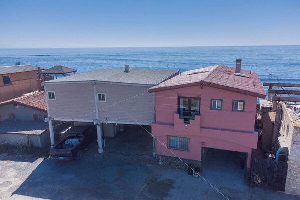 Zona residencial con una casa de dos pisos, un garaje y vista al mar.
