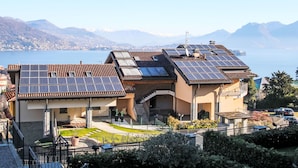 A residential building with solar panels on the roof, a garden, and a view of a lake and mountains. - Baveno View by Interhome (Baveno)