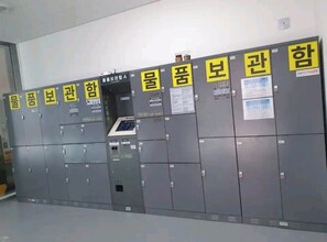 Fila de taquillas grises con etiquetas amarillas y un teclado de seguridad.