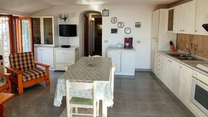 A compact kitchen with a dining table, chairs, a TV, and a coffee maker. - La Favola by Interhome (Ischia)