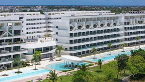 Ein modernes Hotel mit mehreren Etagen, einem zentral gelegenen Schwimmbad und Blick auf die umliegende Landschaft.