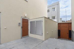 Stylish urban courtyard with a central building and three doors, including a metal shutter door.