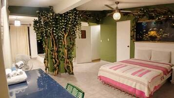 Ein Schlafzimmer mit einem Bett, einem Ventilator, einer grünen Wand und Deckenventilator.