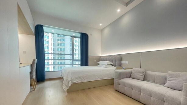 A modern bedroom with a bed, a sofa, a desk, and a large window with curtains. - 2mins walk to Metro station(3 lines), 10mins walk to theme park (Changning)