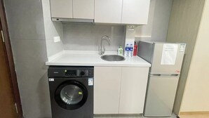 A compact kitchen with a washing machine, a sink, and a refrigerator. - 2mins walk to Metro station(3 lines), 10mins walk to theme park (Changning)