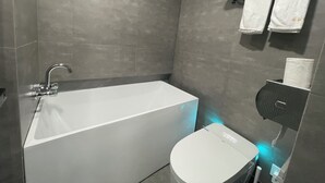 A modern bathroom with a bathtub, toilet, and towel rack. - 2mins walk to Metro station(3 lines), 10mins walk to theme park (Changning)