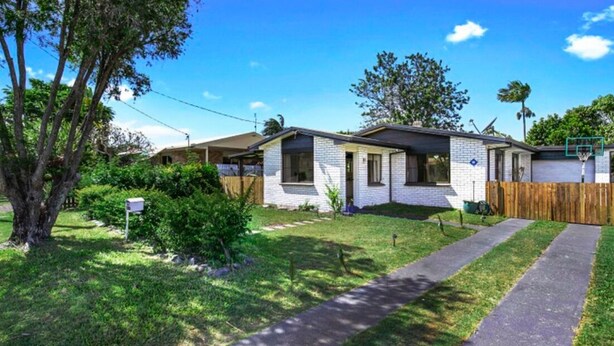 Une maison à deux étages avec un jardin devant, une clôture en bois et une boîte aux lettres.