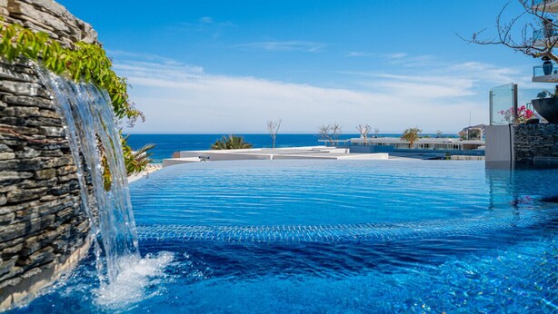 Piscina com cachoeira, vista clara do oceano e design arquitetônico moderno.