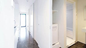 A modern, narrow hallway with a built-in washing machine and a small sink on the right.