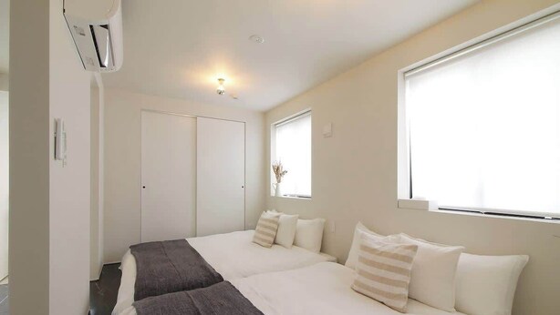 A hotel room with two beds, a window, and a door.