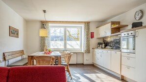 A cozy kitchen with a dining area, wooden furniture, and a view of the outside. - Large holiday apartment, 200m to the ski bus (Fieberbrunn)