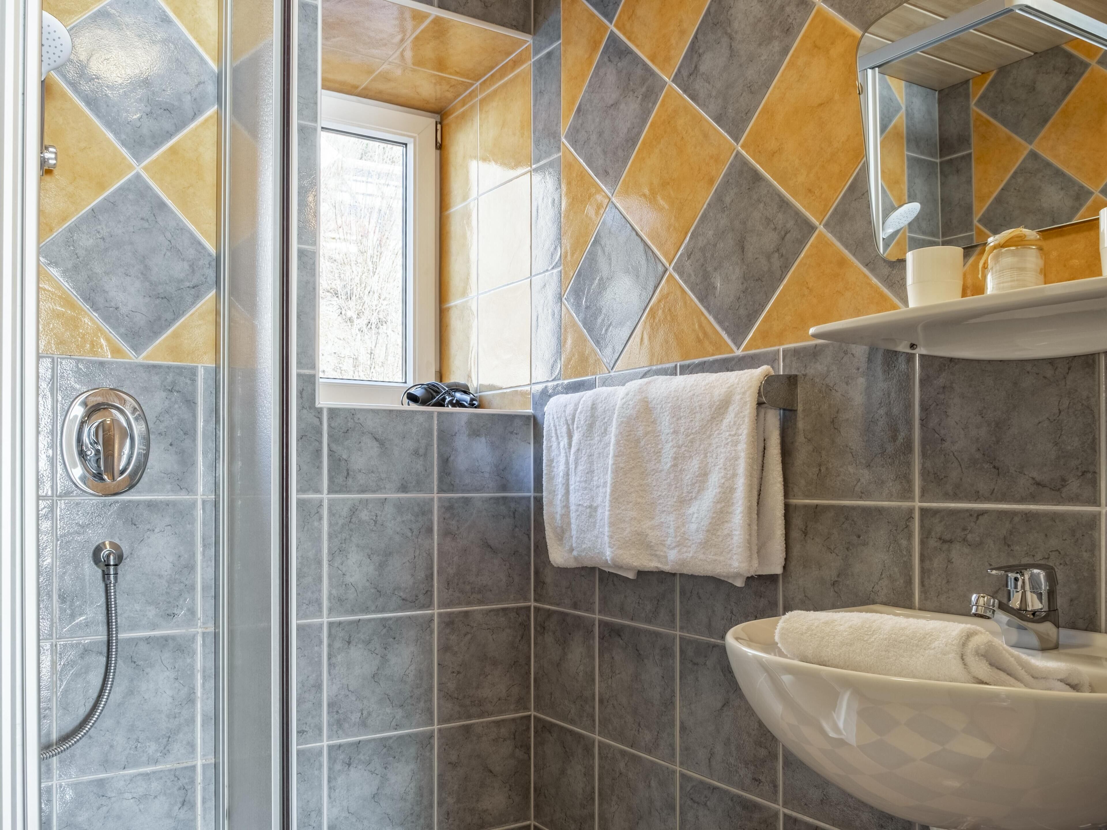 Ein Badezimmer mit Dusche, Waschbecken und Spiegel.