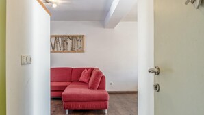 A red sectional sofa in a room with a wooden floor, white walls, and a ceiling light fixture. - Large holiday apartment, 200m to the ski bus (Fieberbrunn)