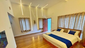 Une chambre spacieuse avec un grand lit, un plancher en bois et une vue sur l’extérieur.