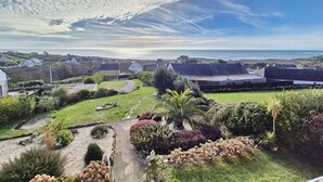 Un village côtier avec des maisons, une zone herbeuse et une vue sur la mer.