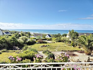 A coastal view with houses, a garden, and a white fence.