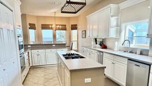 A kitchen with white cabinets, a central island with a stove, and a dishwasher.