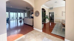 A spacious living area with a large window, a sofa, and a coffee table. There is a potted plant and a rug on the floor.