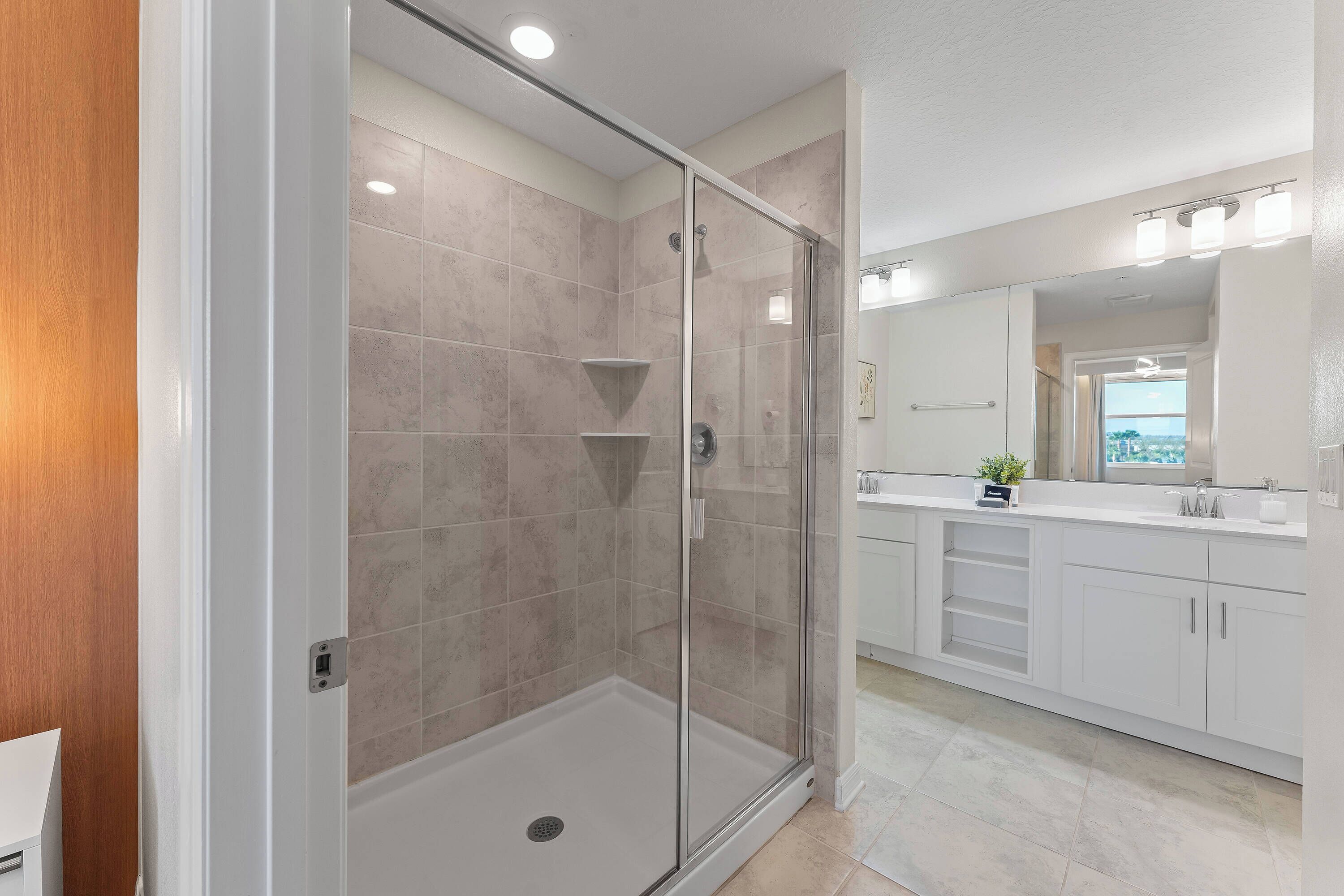 Une salle de bain moderne avec une douche à parois de verre, des meubles blancs et un grand miroir.