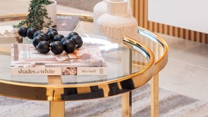A modern room with a glass table displaying a book titled "shades of white" and decorative items.